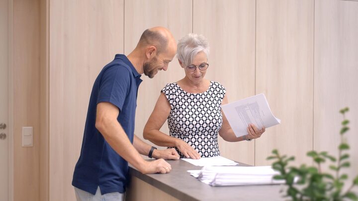 Eine Lehrkraft und eine Schulsekretärin betrachten Formulare