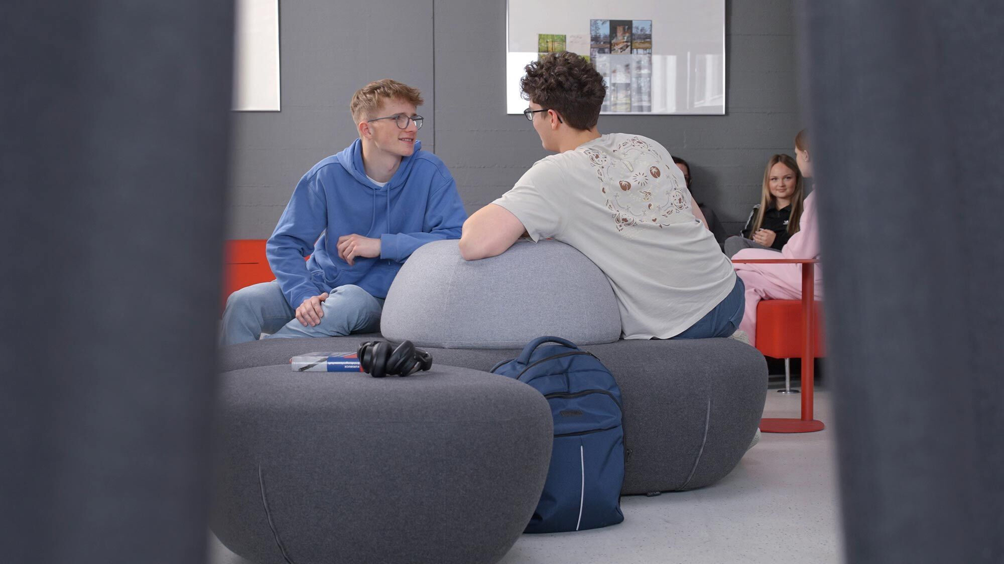 Zwei Schüler unterhalten sich sitzend im Pausen-Aufenthaltsraum