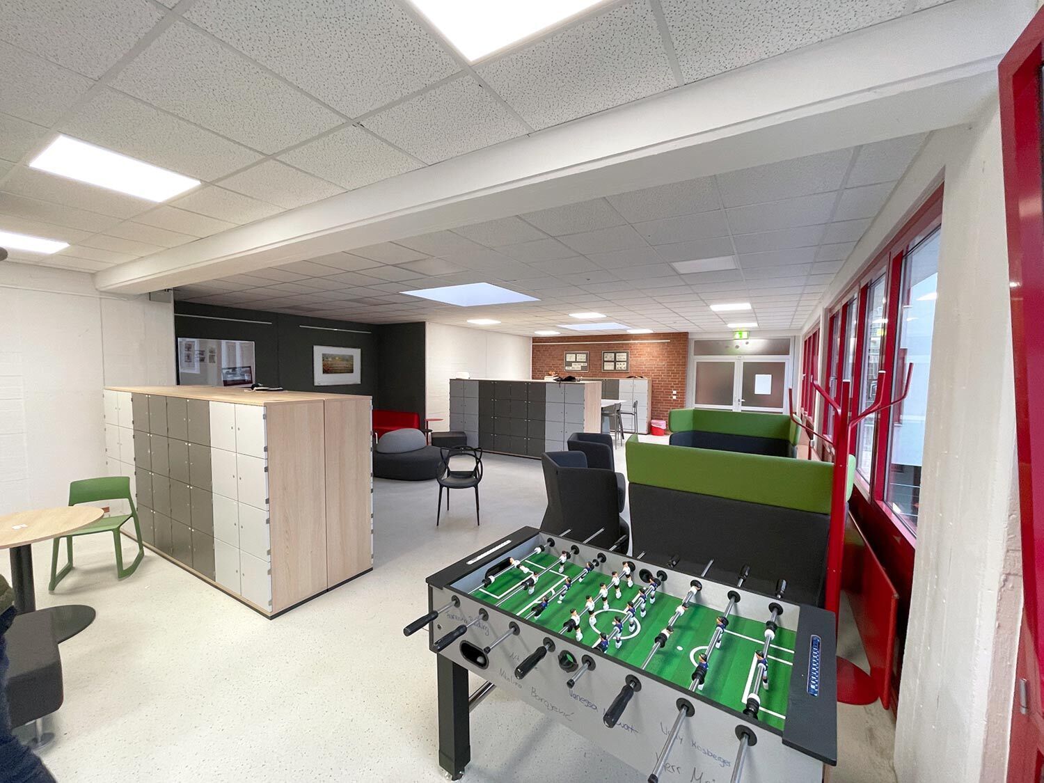 Aufenthaltsraum der Schule mit Sitzgelegenheiten und Tischkicker