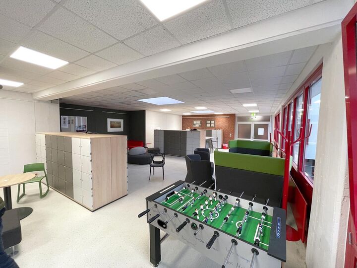 Aufenthaltsraum der Schule mit Sitzgelegenheiten und Tischkicker