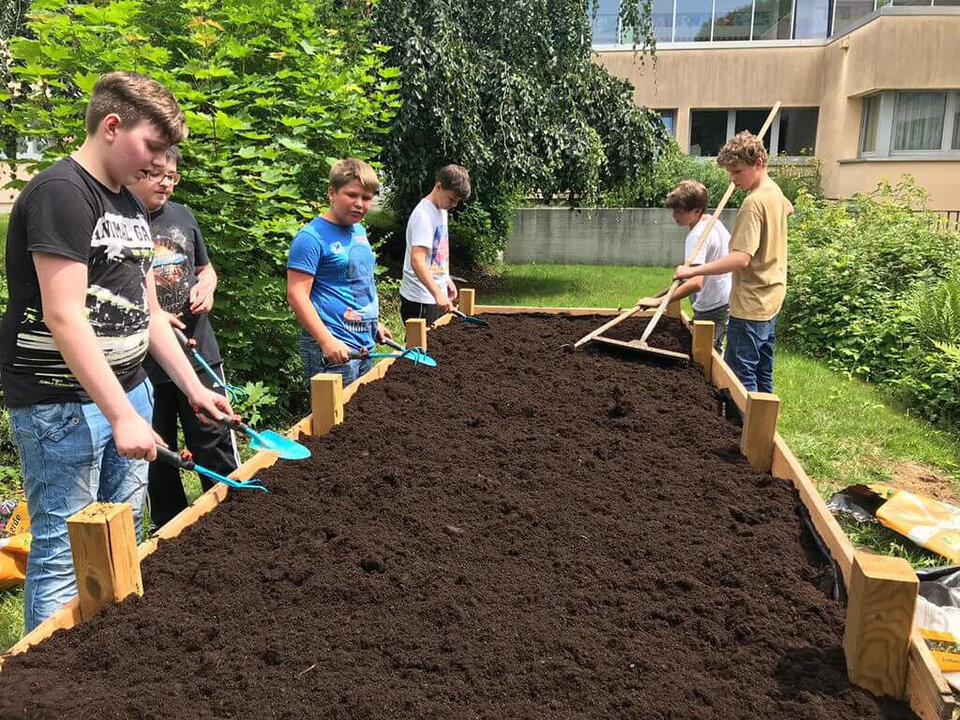 Schüler beim Gärtnern an einem Hochbeet