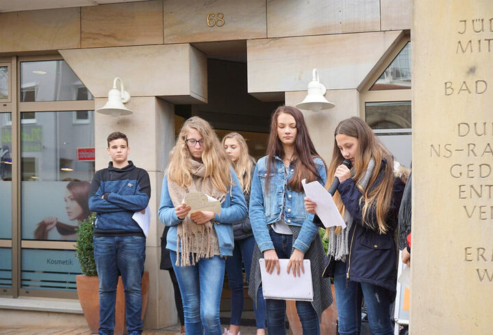 Schülerinnen und Schüler stehen bei einer Gedenkstätte