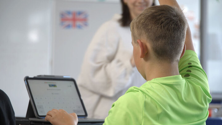 Ein Schüler sitzt vor dem Tablet und meldet sich