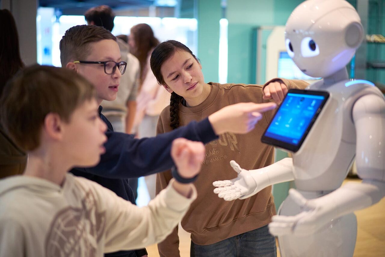 Schüler besuchen den außerschulischen Lernort Heinz-Nixdorf-Museum und stehen vor einem Roboter