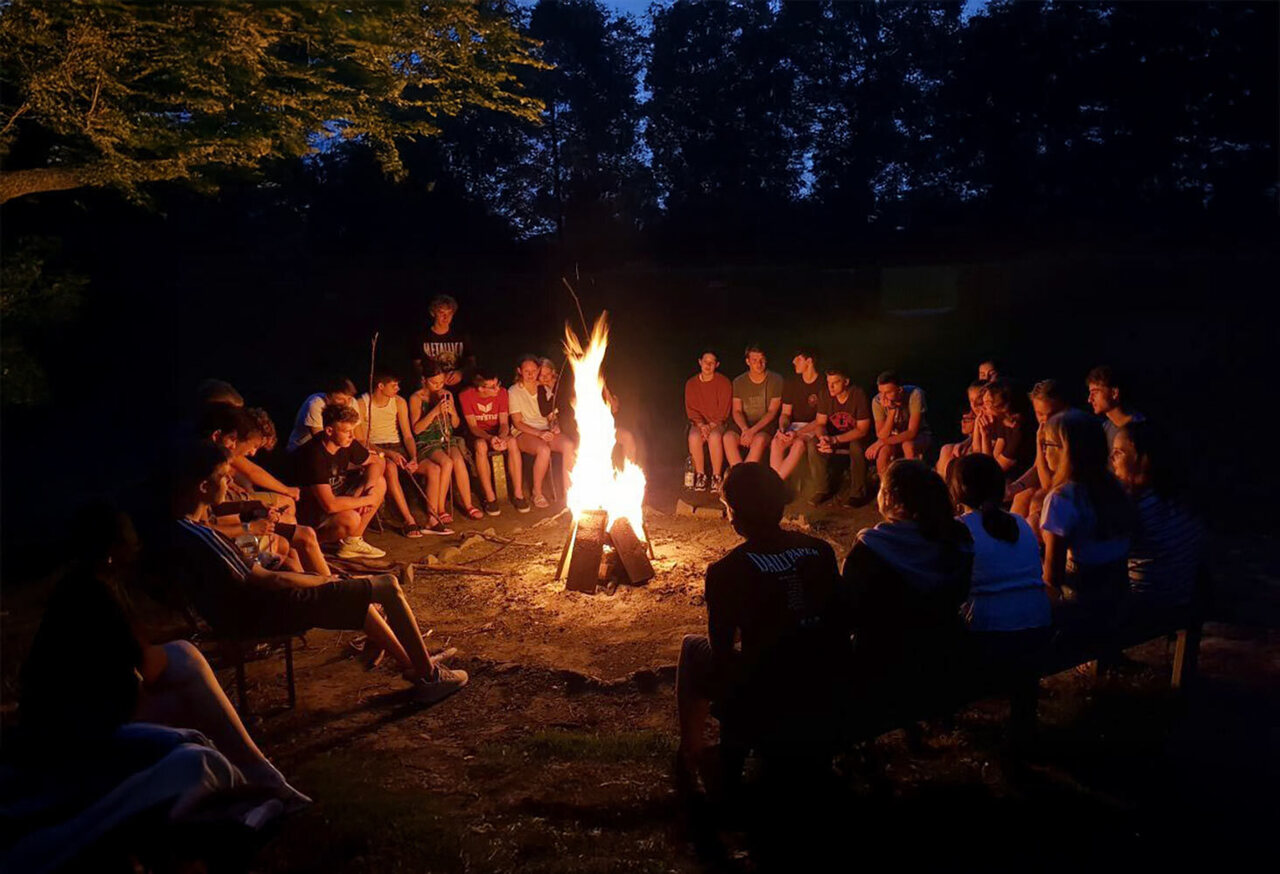 Schüler sitzen um ein Lagerfeuer