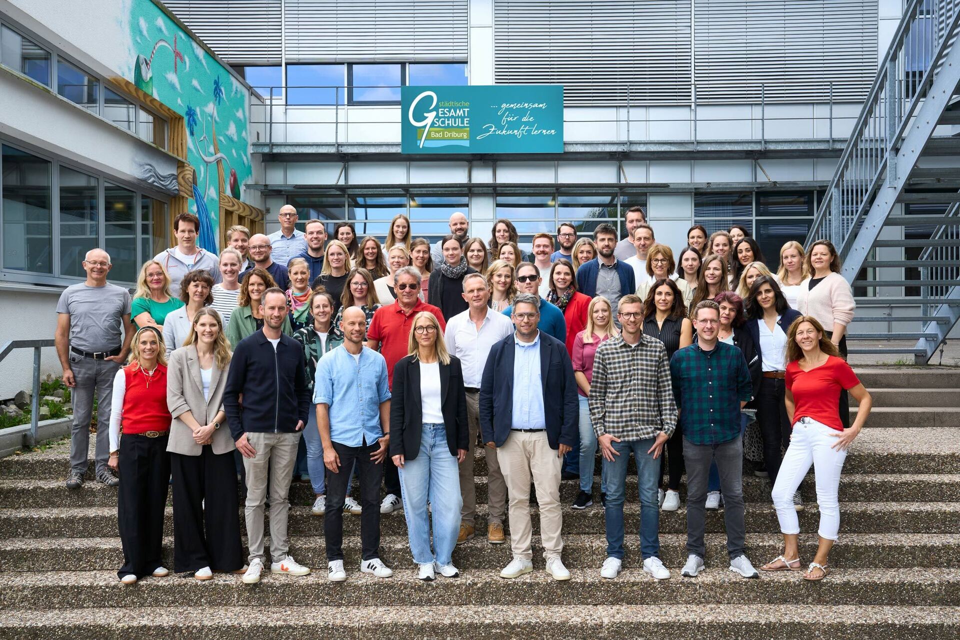 Das gesamte Kollegium steht auf einer Treppe vor der Schule