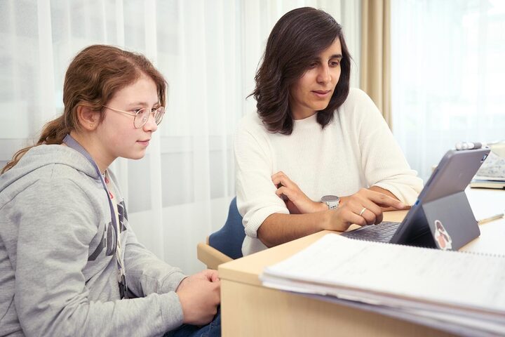 Eine Lehrerin zeigt einer Schülerin etwas auf dem Tablet